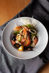 Seafood made dish with king prawns, mussels, squid, greens and citrus as an appetizer in a fancy expensive restaurant