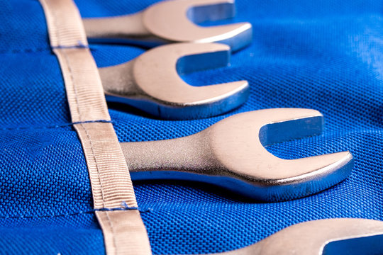 chrome wrenches lying each in its own pocket of fabric blue, close-up photograph