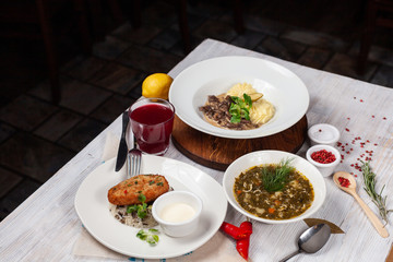 Top view of a three course set menu: beef stroganoff with mashed potatoes, turkey cutlet with rice and hot sorrel soup