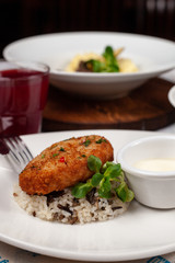 Close up of crunchy breaded cutlet with white steamed basmati rice as a part of restaurant set menu, served in a white plate