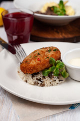 Close up of crunchy breaded cutlet with white steamed basmati rice as a part of restaurant set menu, served in a white plate