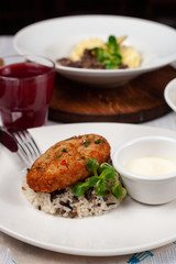 Close up of crunchy breaded cutlet with white steamed basmati rice as a part of restaurant set menu, served in a white plate