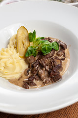 Classic russian beef stroganoff with white gravy and mashed potatoes served in a white plate
