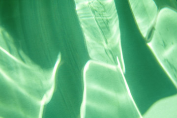Trendy mint colored abstract background with light and shadows caustic effect. Light passes through a glass.