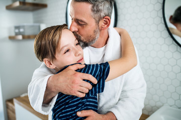 Mature father with small son in the bathroom in the morning, kissing.