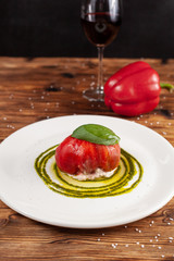 Bull's Heart tomato, stuffed with tuna and cheese, flavoured with fresh pesto sauce and basil on a white plate