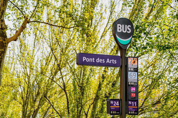 Ponts des Arts (Bridge of Arts) bus stop sign in Paris, France. Green leaves tree in spring. 