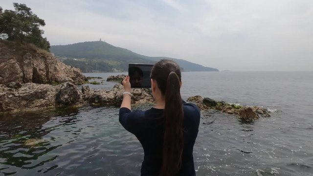 Asian-looking tourist girl takes pictures of Islands, rocks and the sea in Turkey