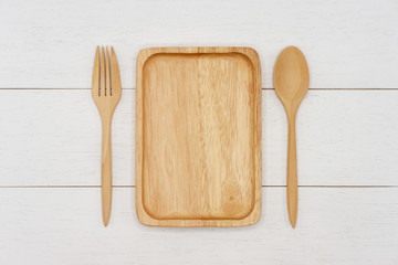 Empty rectangle wooden plate with spoon and fork on white wooden table. Top view image.