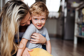 A happy mother with a toddler son indoors at home. Copy space.