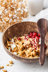 Homemade granola with cranberries and peanut butter in a coconut bowl, vertical.