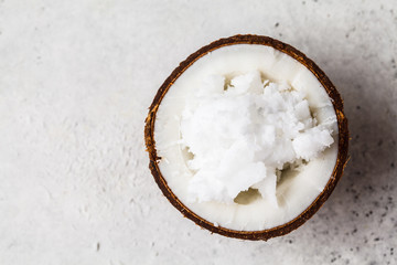 Coconut oil in a coconut shell on gray background, top view.