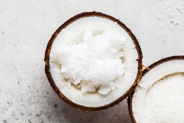 Coconut oil in a coconut shell on gray background, top view.
