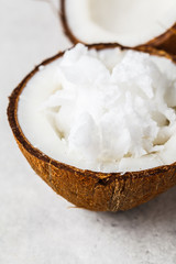 Coconut oil in a coconut shell on gray background.
