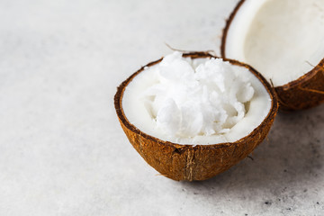 Coconut oil in a coconut shell on gray background.