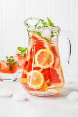 Grapefruit lemonade with lemon and mint in glass jug.