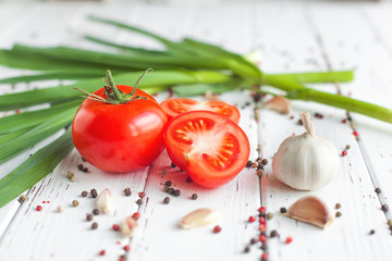 Fresh tomatoes with spices. Organic healthy food on wooden background. Green garlic. Summer and autumn vegetables.