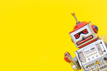 Antique tin toy robot on yellow background. Vintage and classic concept free copy space for text. - obrazy, fototapety, plakaty