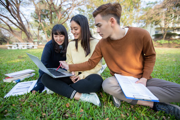 Group Of University Students asian sitting on the green grass  Working and reading Outside Together in a park