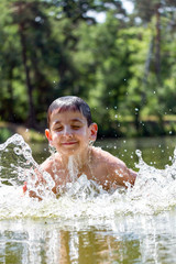 boy swims in the lake. Around a lot of spray and foam