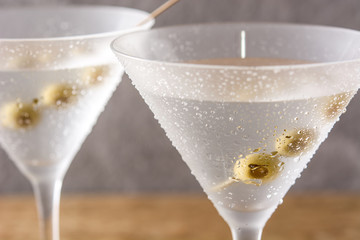 Classic Dry Martini with olives in glass on wooden table