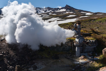 Emission of natural mineral thermal water, steam (steam-water mixture) from geological well in geothermal deposit area, geothermal power plant on slope of active Mutnovsky Volcano. Kamchatka Peninsula