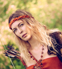 Beautiful girl archer with long blond hair with a bow and arrows dressed in leather