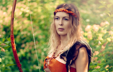 Beautiful girl archer with long blond hair with a bow and arrows dressed in leather