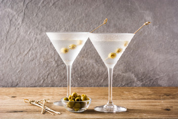 Classic Dry Martini with olives on wooden table and gray background