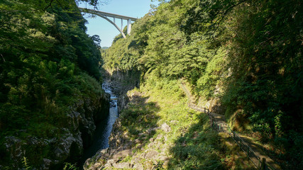 Fototapeta premium Takachiho Gorge is a narrow chasm cut through the rock by the Gokase River. The nearly sheer cliffs lining the gorge are made of slow forming volcanic basalt columns.