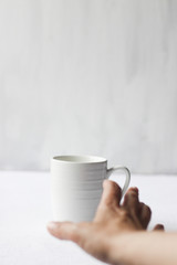 Coffee addiction, white coffee mug and hand