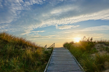 Wooden path at Baltic sea over sand dunes with ocean view, sunset summer evening