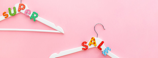 White hangers with sale text on pink background