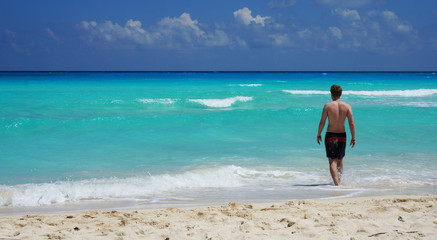Fototapeta na wymiar Man going to swim in Caribbean sea, Cancun beach, Mexico.