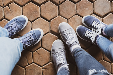 Three pairs of woman’s and child’s legs; wooden background.