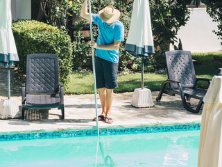 A man cleans a swimming pool outside.