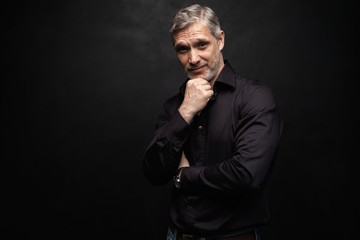 Fototapeta premium Middle-aged good looking man posing in front of a black background with copy space.