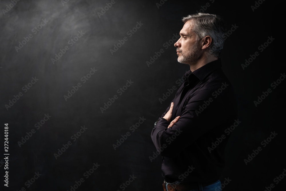 Wall mural Middle-aged good looking man posing in front of a black background with copy space.