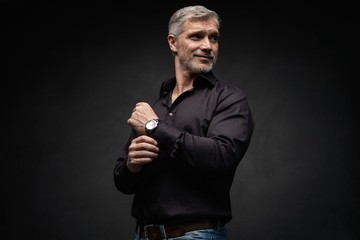 Middle-aged good looking man posing in front of a black background with copy space.