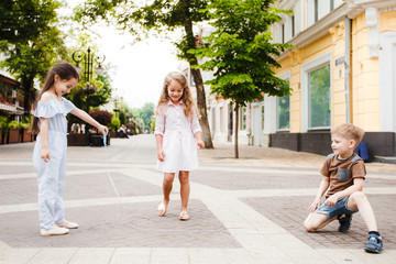 Fototapeta premium Little friends are walking around the city. Play and have fun. Three jump over the rope.