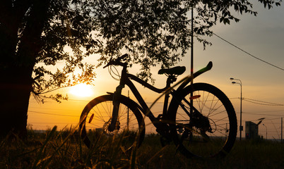 Fototapeta na wymiar Beautiful close up scene of bicycle at sunset, sun on blue sky with vintage colors, silhouette of bike forward to sun.