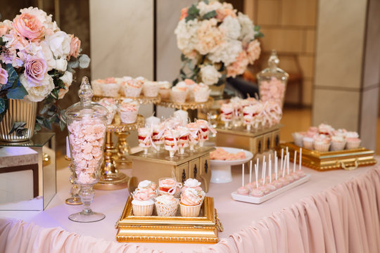 Candy bar on table in vase and plate, macaroon, marshmallow, cake and cupcake