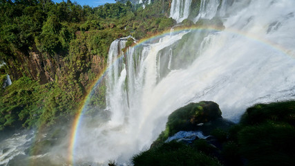 Fototapeta premium Iguazu Falls and a round rainbow on the Iguacu River. Located between Argentina and Brazil. Largest waterfalls system in the world.