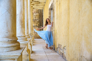 Young woman in blue airy skirt is elegance posing in the ancient ruins corridor with greek columns in Macao China