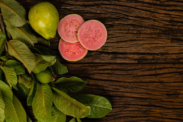 Fresh red guavas with green leaves on wooden demolition background. Wood texture and guava leaves.