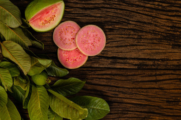 Fresh red guavas with green leaves on wooden demolition background. Wood texture and guava leaves.