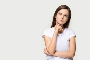 Pensive young caucasian woman thinking isolated on studio grey background