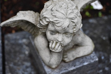 A white statue of a small angel on a christian cemetery in Berlin-Germany.