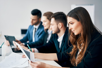 smiling group of business people sitting in row together at table in modern office
