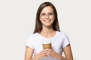 Attractive girl holding coffee cup pose over grey studio background